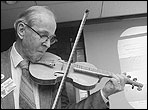 Oliver Rodgers tests a fiddle by Marty Kasprzyk