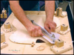 Tom Ribbecke using a jig to fit the X brace of a archtop guitar