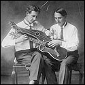 Old photo of one handed players playing a harp guitar