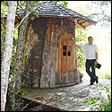 Michael Sanden stands next to a log house made from a single lollow log