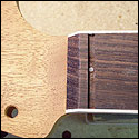 The fretboard gets pinned to the neck