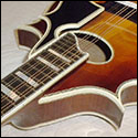 A view of the binding along the neck, body, soundhole, and pickguard of a mandolin