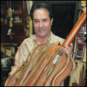 Manuel Diaz holds a clear plastic guitar he made to show of his longitudinal bracing pattern