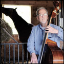 Color photo of Arnold Schnitzer with a upright bass inside a barn